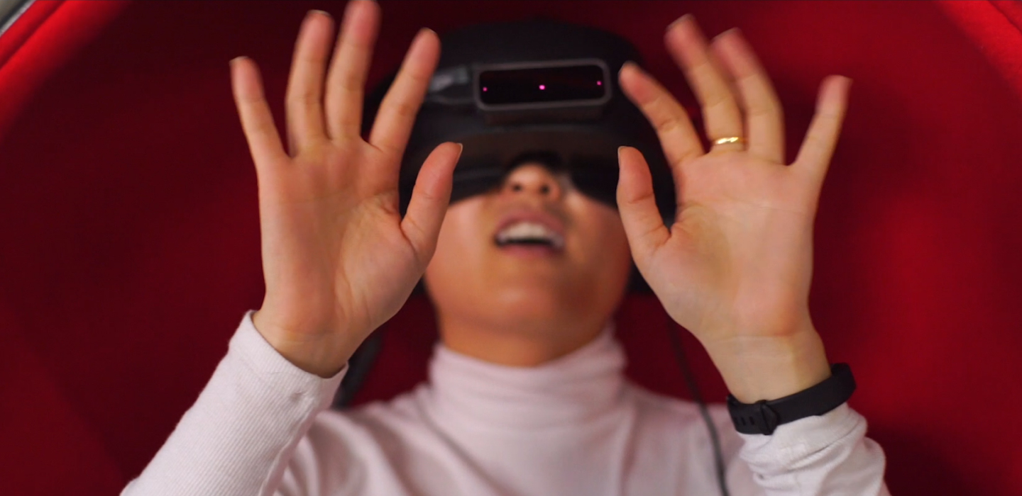 A woman experiencing virtual reality. Her hands are reaching toward the screen