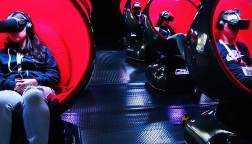People sitting in a row of Voyager motion chairs with VR headsets on.