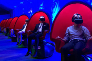 A row of red positron chairs with people sitting in them, with a glowing blue background